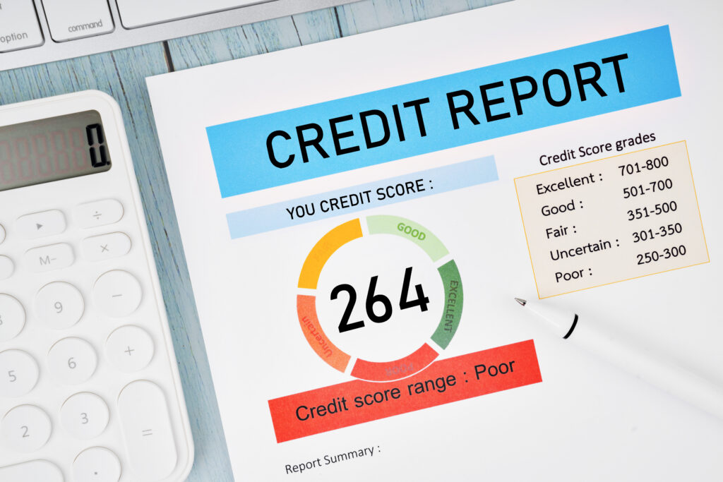 A credit report on a desk shows a credit score of 264, which falls into the 'Poor' range.