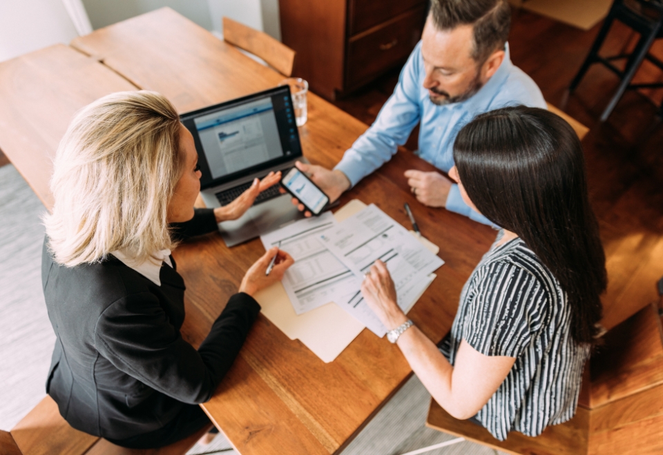 Three professionals reviewing documents and financial reports at a meeting, highlighting financial mistakes professionals make.