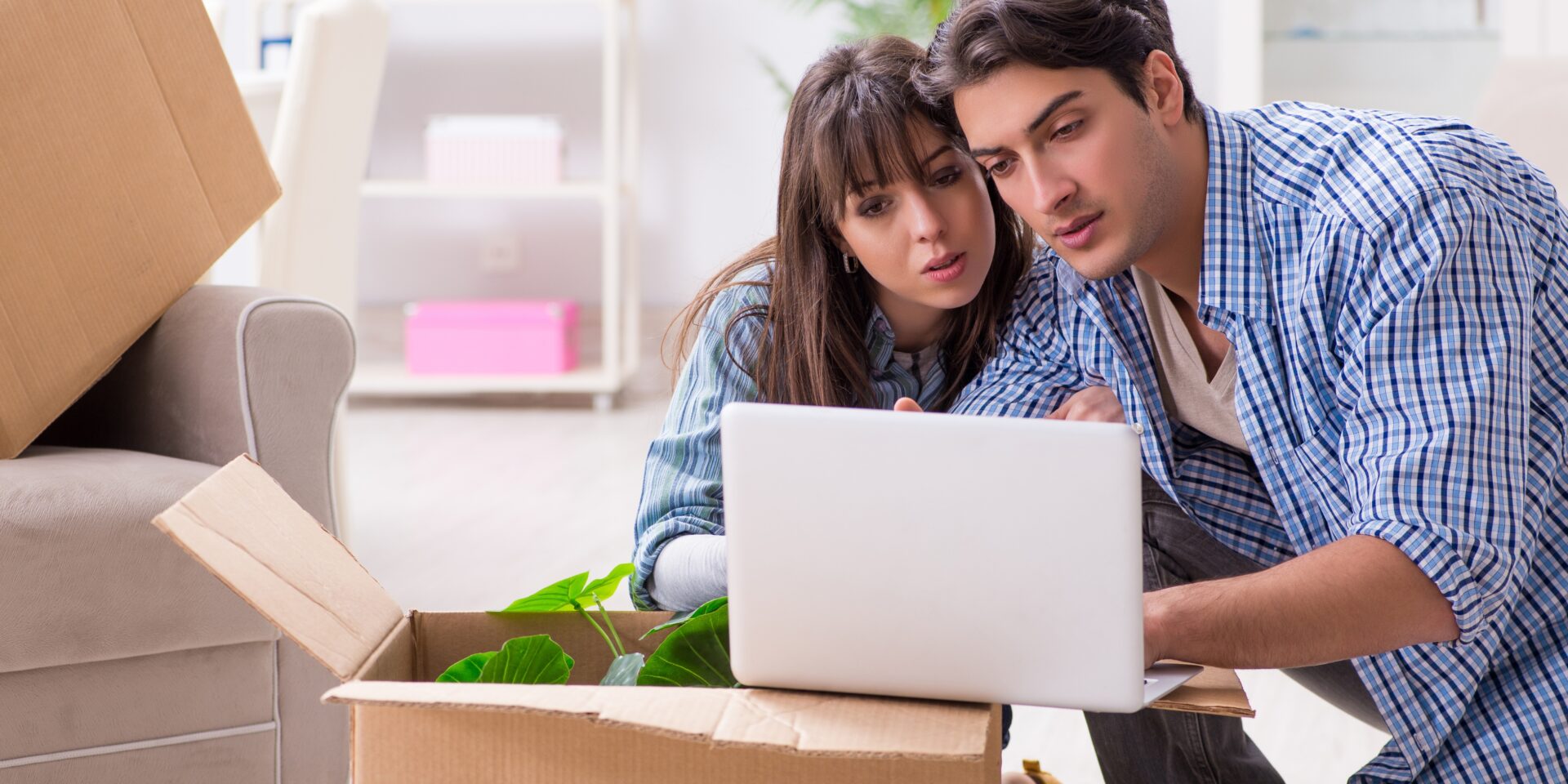 A couple sitting among moving boxes, focused on a laptop as they plan smart strategies to pay off their mortgage faster.