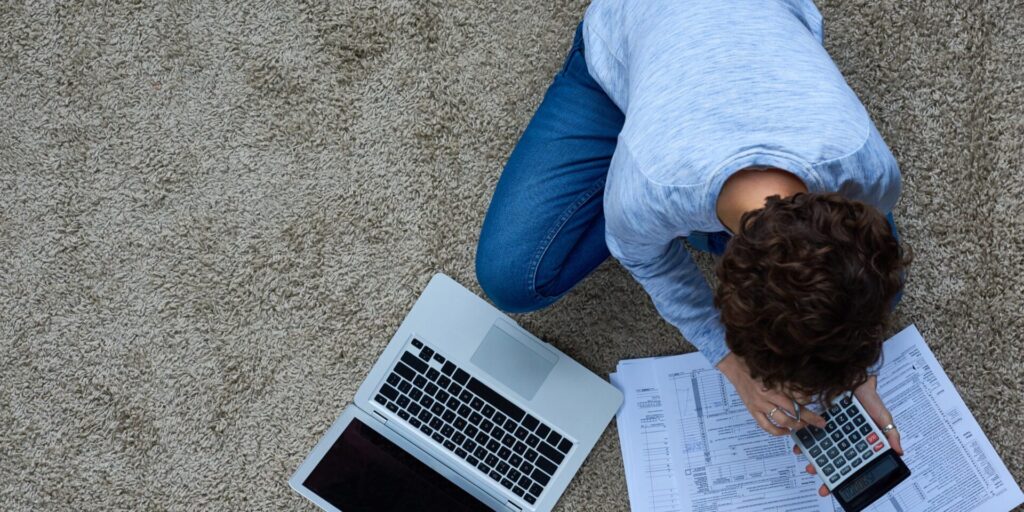 Person calculating finances at home with a laptop and paperwork, symbolising the need for insurance for sole traders.