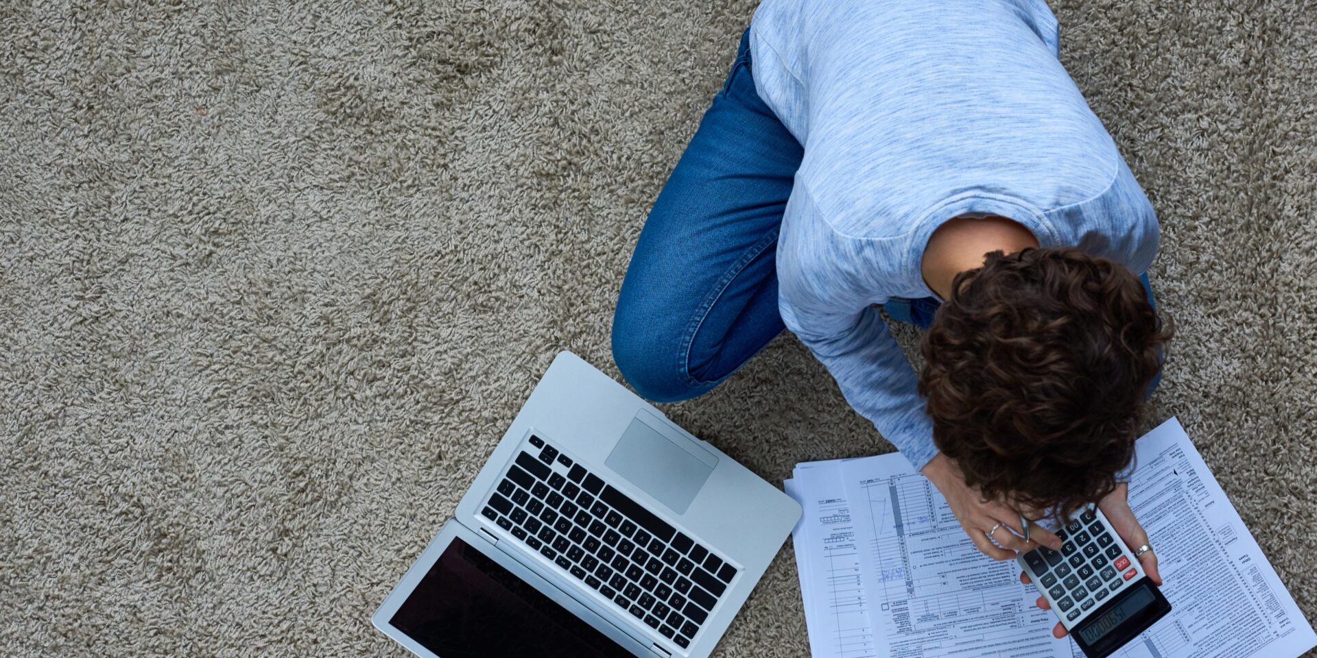 Person calculating finances at home with a laptop and paperwork, symbolising the need for insurance for sole traders.