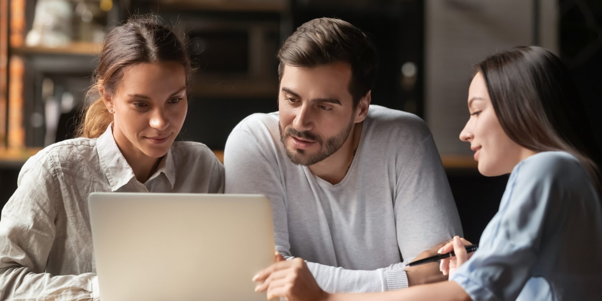People discussing business insurance options while reviewing documents on a laptop.